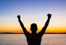 Vencendo Gigantes uma foto de uma pessoa com as maos levantadas olhando par horizonte