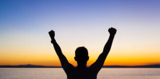 Vencendo Gigantes uma foto de uma pessoa com as maos levantadas olhando par horizonte