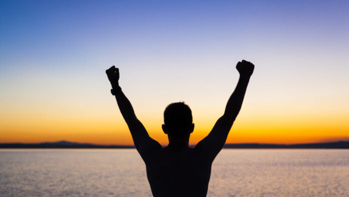 Vencendo Gigantes uma foto de uma pessoa com as maos levantadas olhando par horizonte