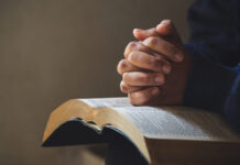 Perseverança e fé em Deus foto de uma pessoa com a bíblia no colo e com as maos em cima e os dedos cruzados