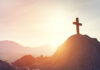 Imagem do por do soul e uma cruz em cima de uma montanha