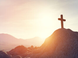 Imagem do por do soul e uma cruz em cima de uma montanha